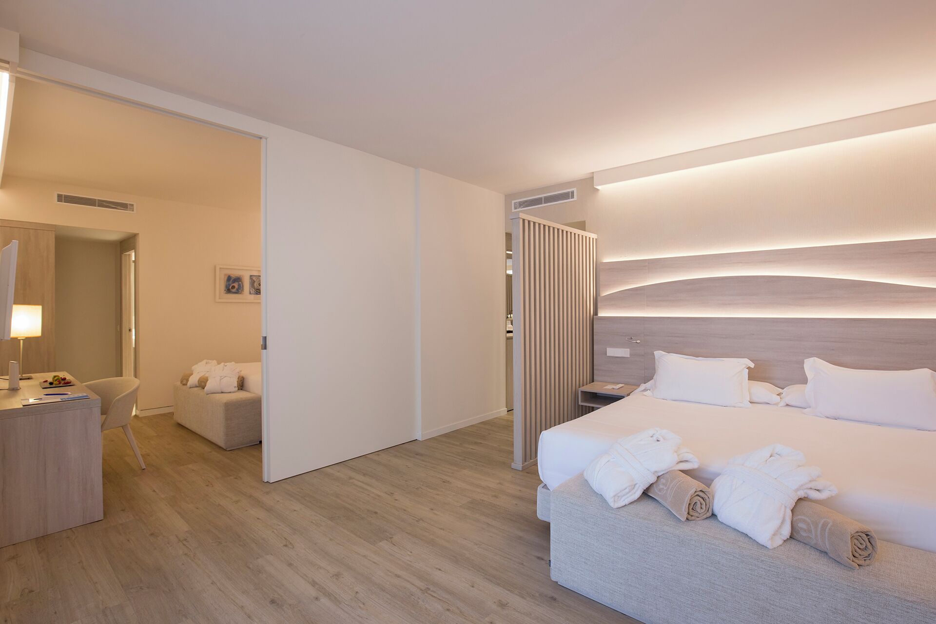 Una habitación de hotel moderna con una cama grande, mesitas de noche, un escritorio y un área de descanso.