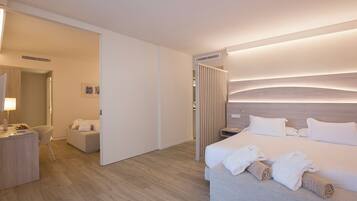 Una habitación de hotel moderna con una cama grande, mesitas de noche, un escritorio y un área de descanso.