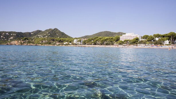 A coastal area with clear blue water, a sandy beach, and buildings along the shore. - Canyamel Park Hotel & Spa - Adults Only (Capdepera)