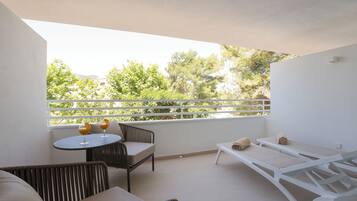 A balcony with a sofa, a small round table with glasses, and a sun lounger.