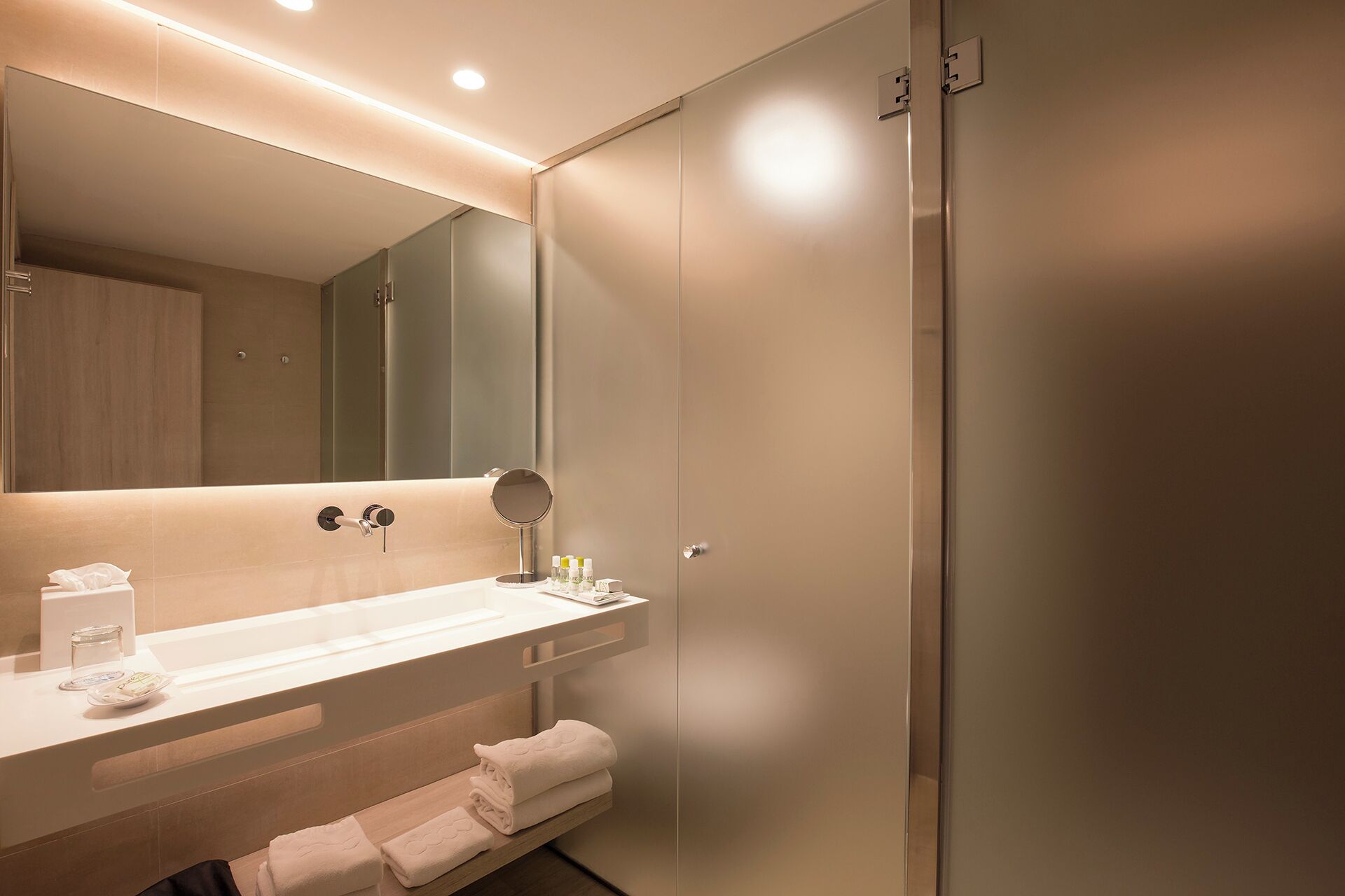 Un baño moderno con un espejo grande, un lavamanos y un inodoro.