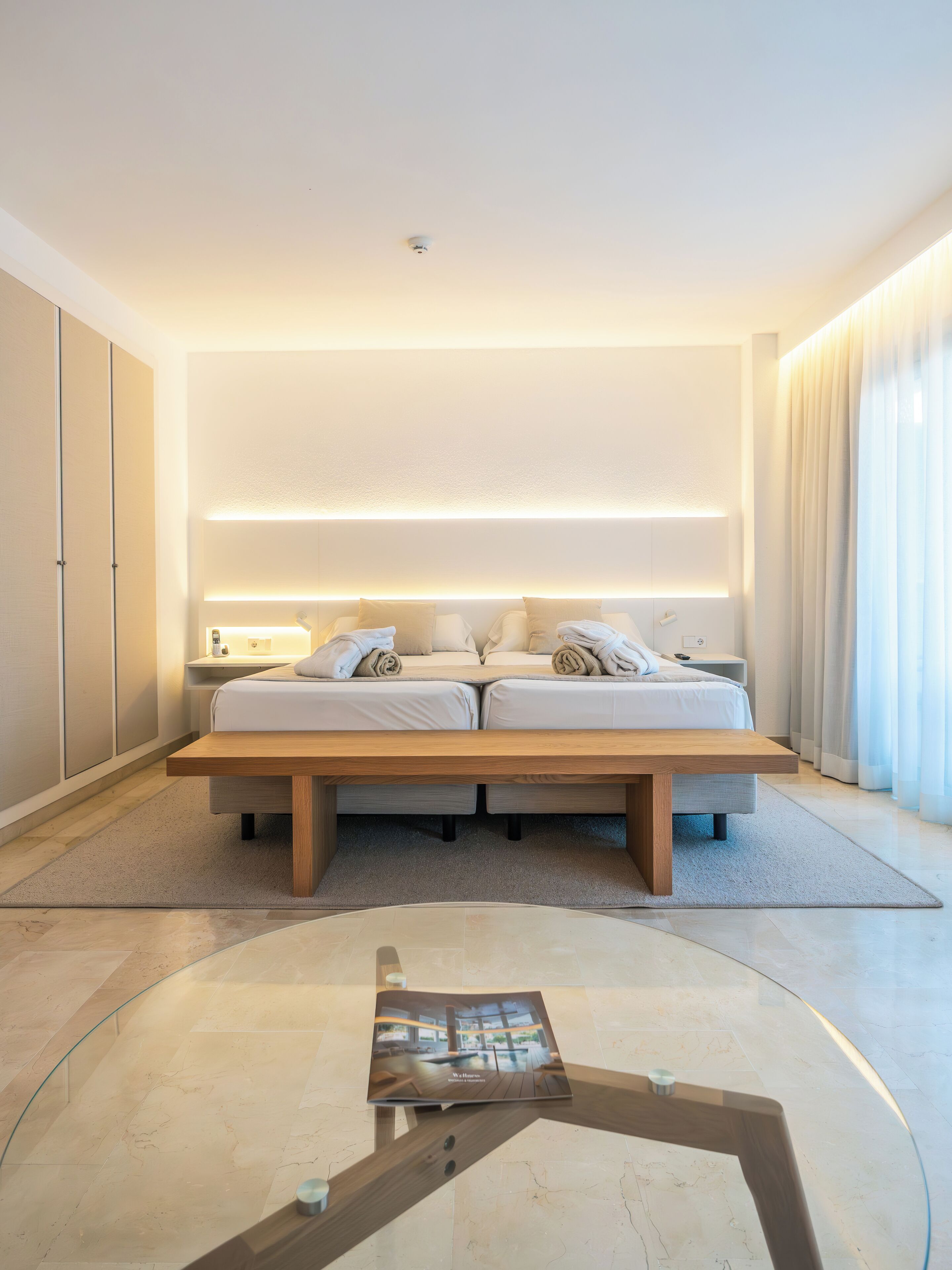 Ein modernes Schlafzimmer mit einem großen Bett, Nachttischen und einem Glastisch.
