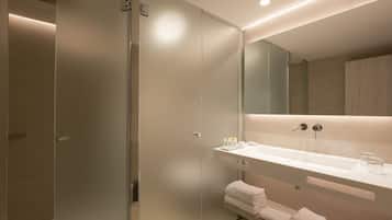 Un baño moderno con un espejo grande, un lavamanos blanco y toallas dobladas con cuidado.