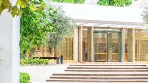 A modern building entrance with a glass door, steps leading up to it, and a wooden fence. - Canyamel Park Hotel & Spa - Adults Only (Capdepera)