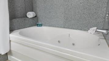 Een wit bad met douchegordijn, een handdoek en toiletartikelen op een plank.