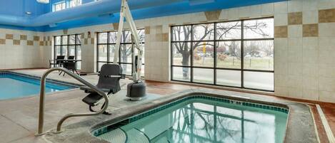 Une piscine intérieure avec des parois en verre transparent, une échelle et un poste de surveillance pour le sauveteur.