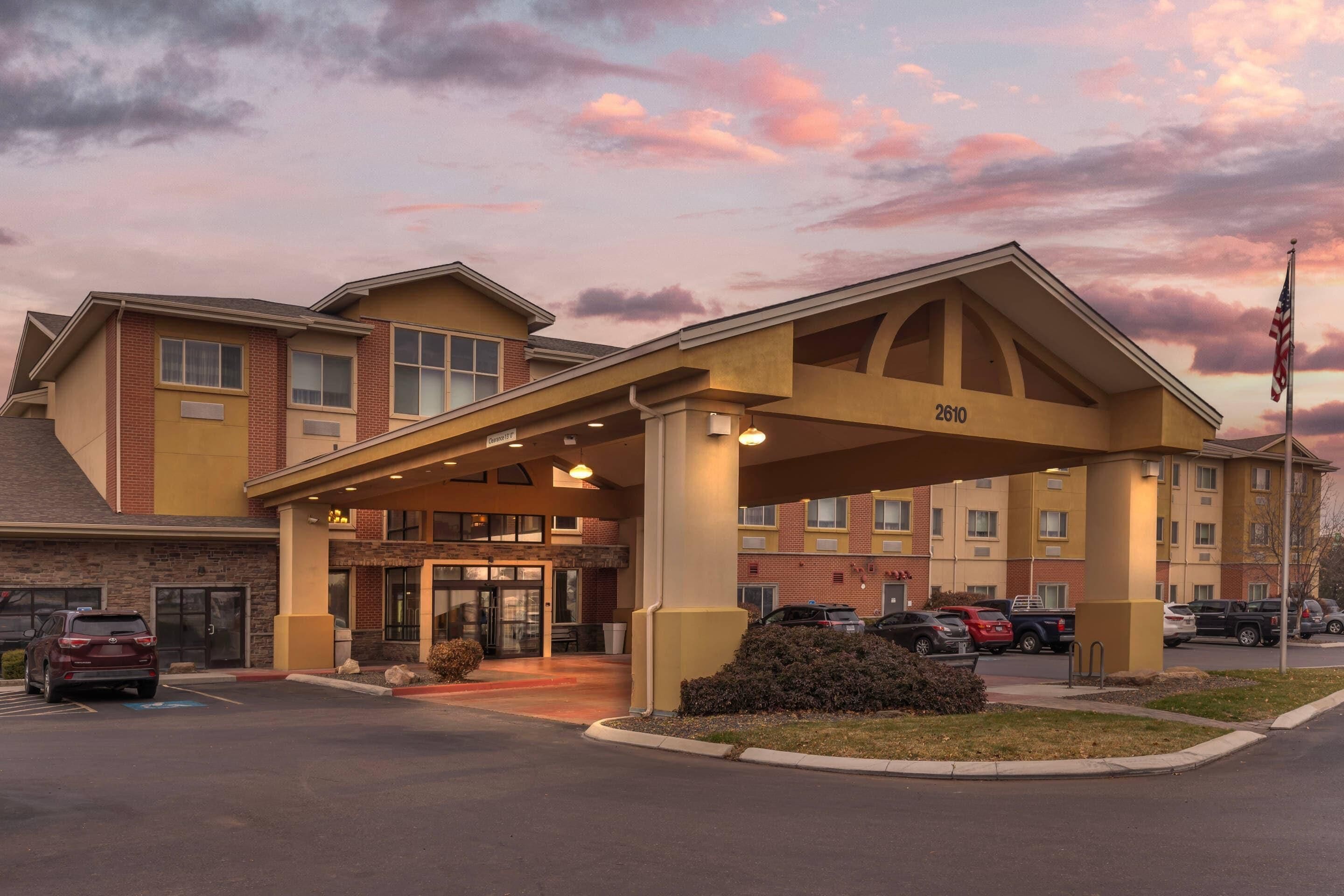 A hotel with a covered entrance, numbered 2610, and a parking lot with several cars.