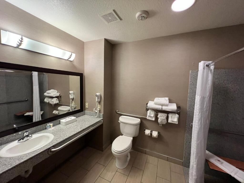 A bathroom with two sinks, a toilet, a shower, and a towel rack.