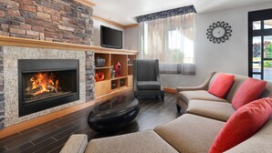Una sala de estar con chimenea de piedra, un televisor de pantalla plana, un sofá cómodo y una silla moderna.