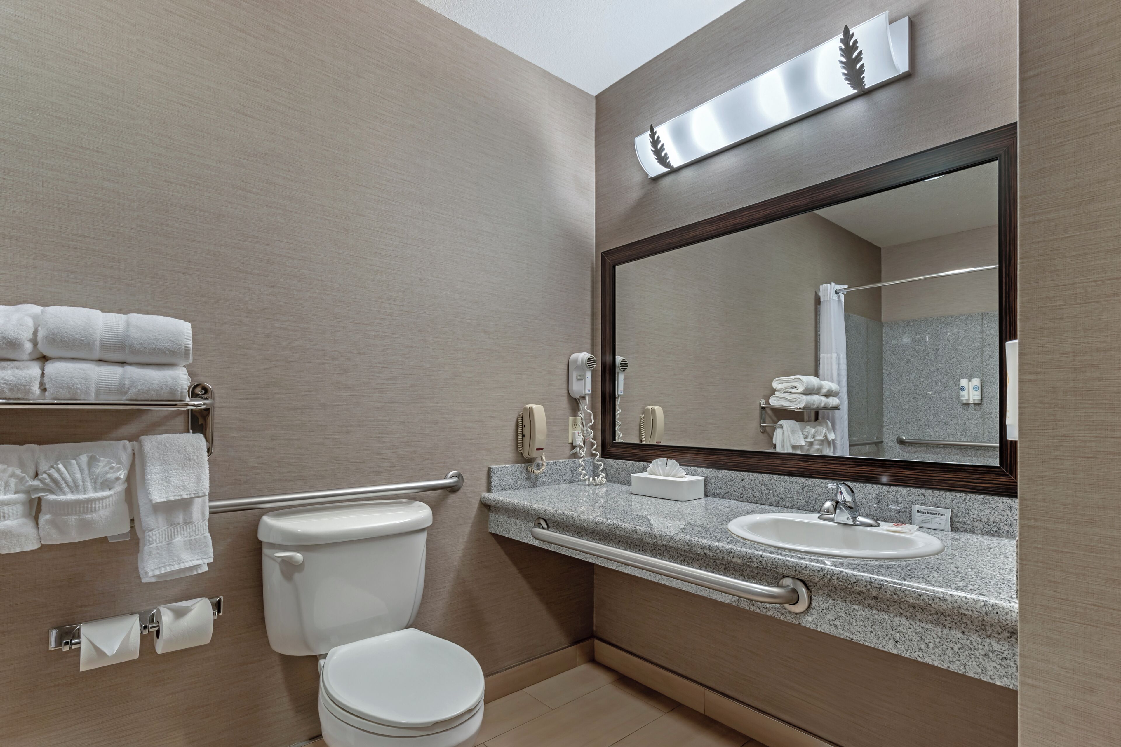 A modern bathroom with a toilet, sink, and large mirror.