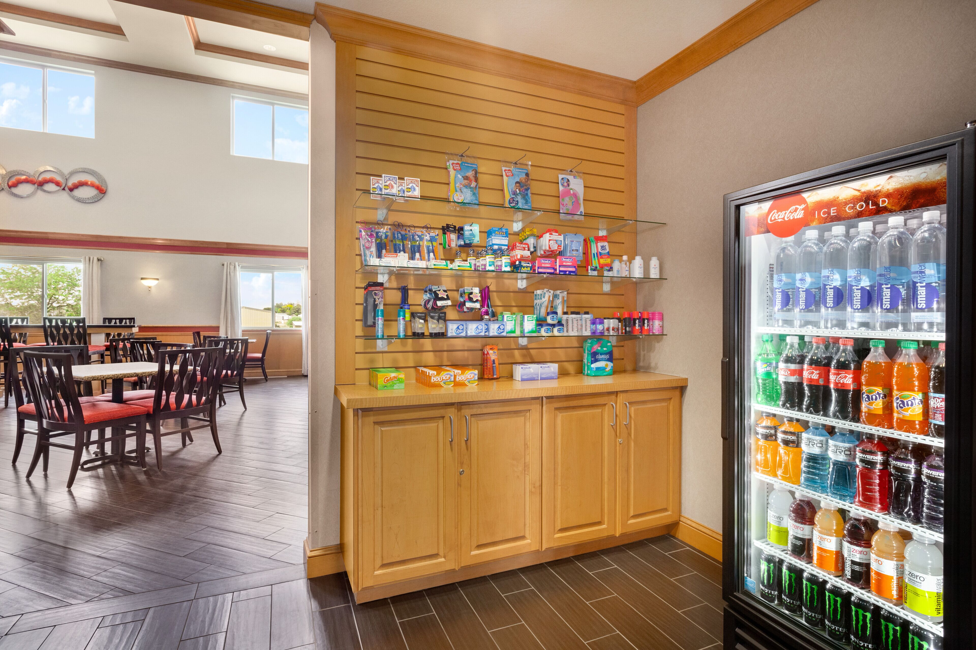 A restaurant with wooden cabinets, a Coca-Cola refrigerator, and various food items on shelves.