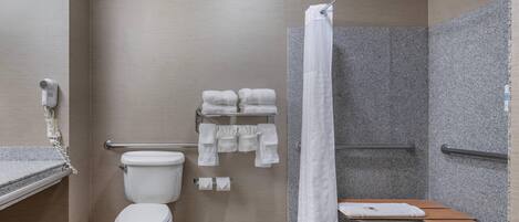 A modern bathroom with a toilet, shower, and a bench.
