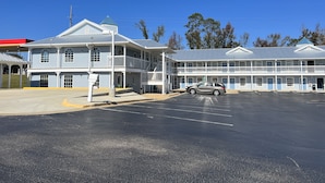 A two-story motel with a parking lot and a single car parked in front. - Key West Inn - Millbrook (Millbrook)