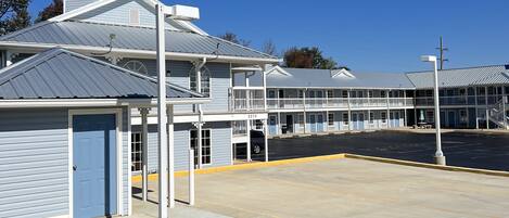 A motel with a parking lot, a covered area, and a building with a blue door.