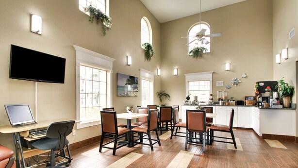 A spacious dining area with high ceilings, large windows, and a modern kitchen area. - Key West Inn - Millbrook (Millbrook)