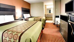 A hotel room with two beds, a television, a desk, and a bathroom visible in the background. - Key West Inn - Millbrook (Millbrook)