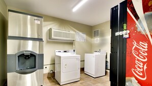 A laundry room with a stainless steel refrigerator, two white washing machines, and an air conditioning unit. - Key West Inn - Millbrook (Millbrook)