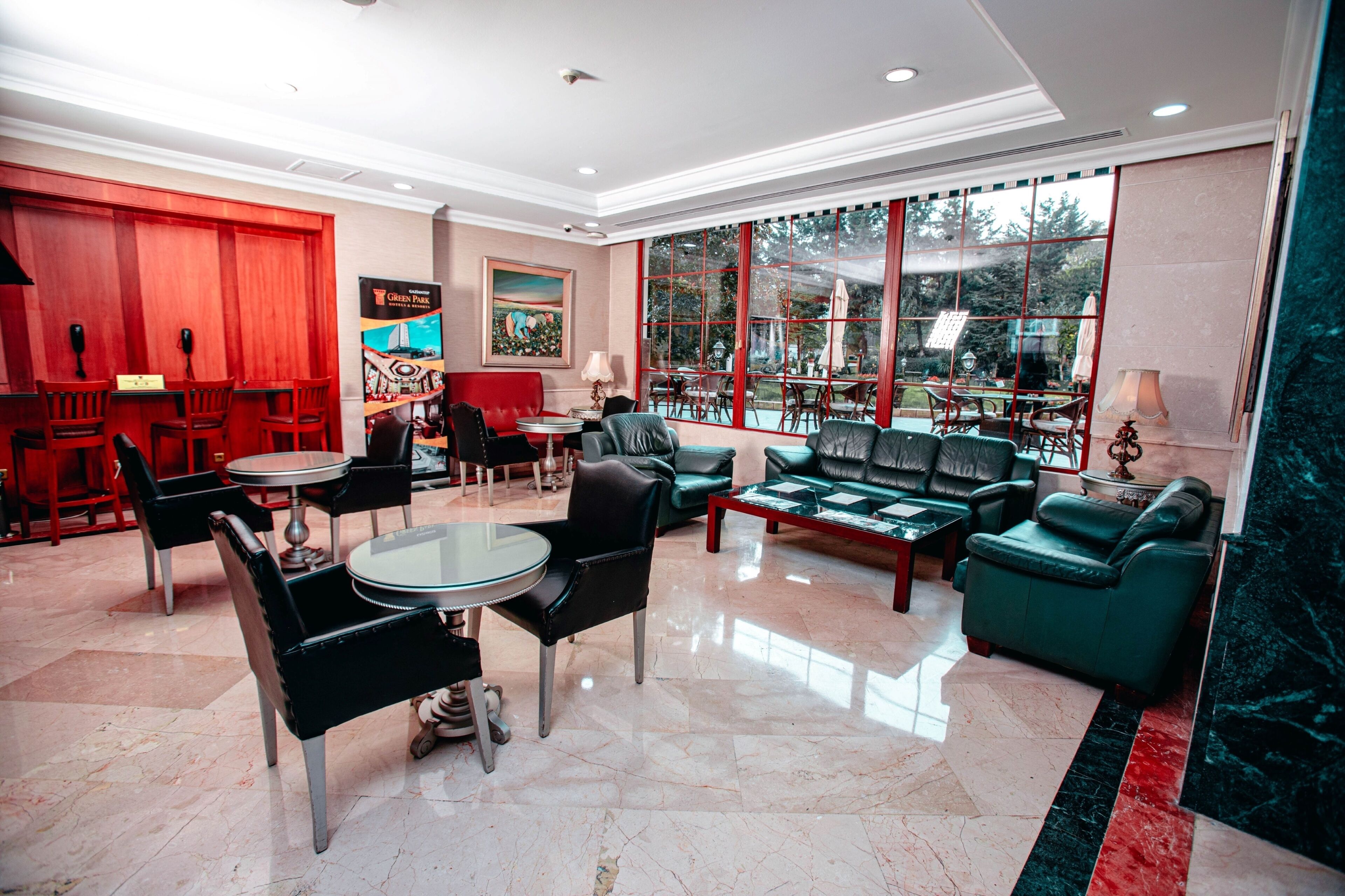 A spacious lobby with a seating area, a reception desk, and large windows offering a view of the outdoors.