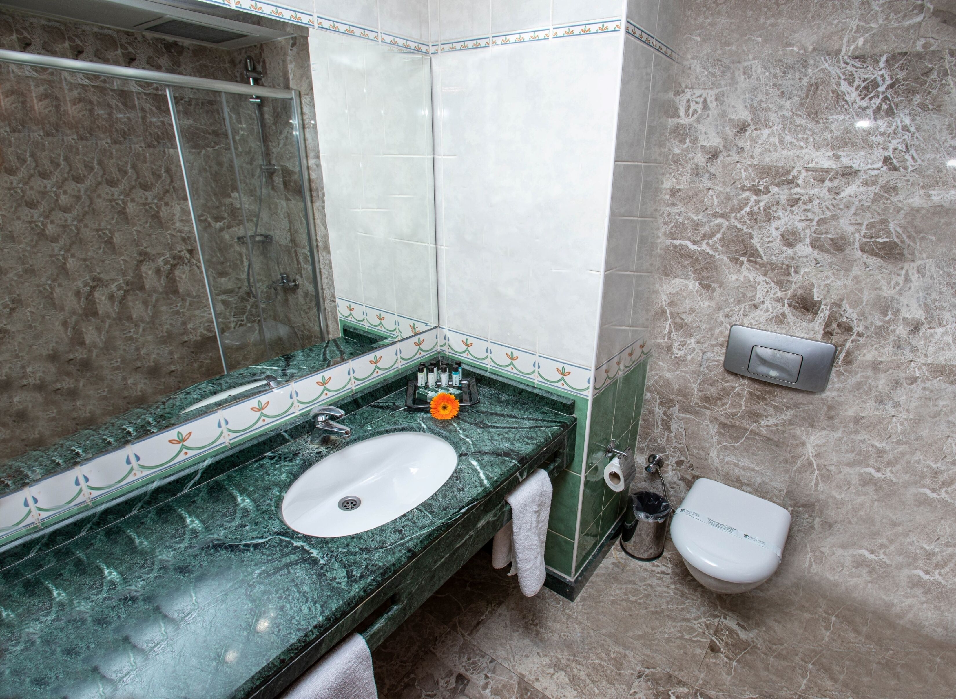 Une salle de bain avec un lavabo en marbre, un miroir, un porte-serviettes et des toilettes.
