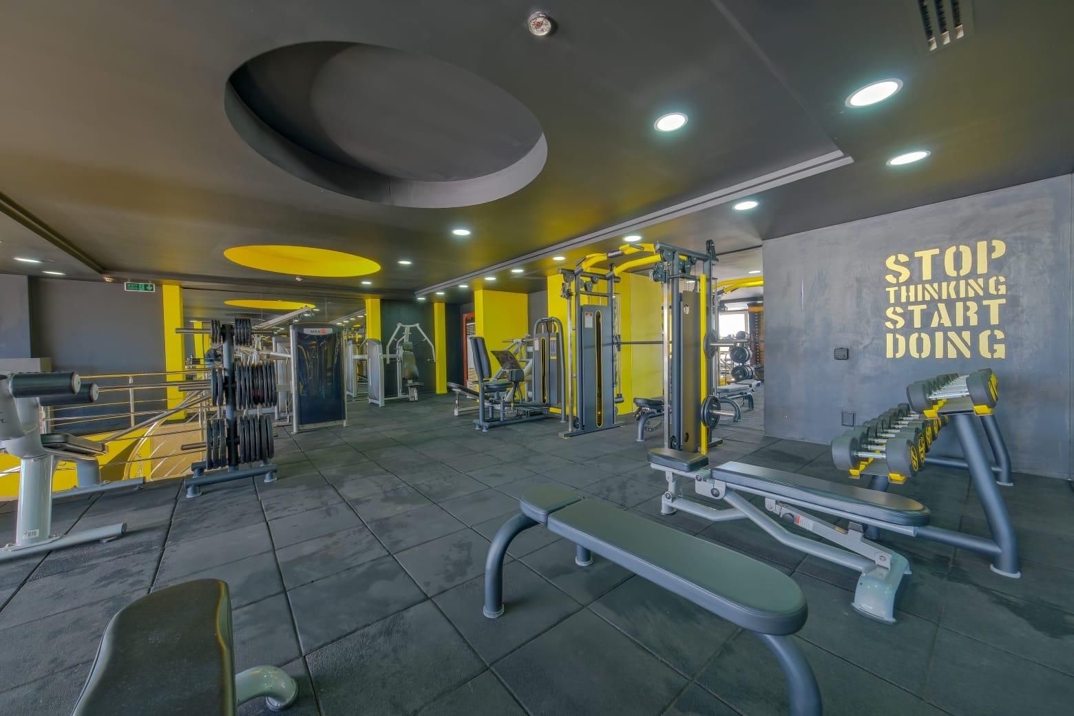 A gym with various exercise equipment, a motivational quote on the wall, and a clean, modern design.