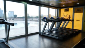 A gym with treadmills and a view of a body of water through large windows. - The Green Park Bostancı (Istanbul)