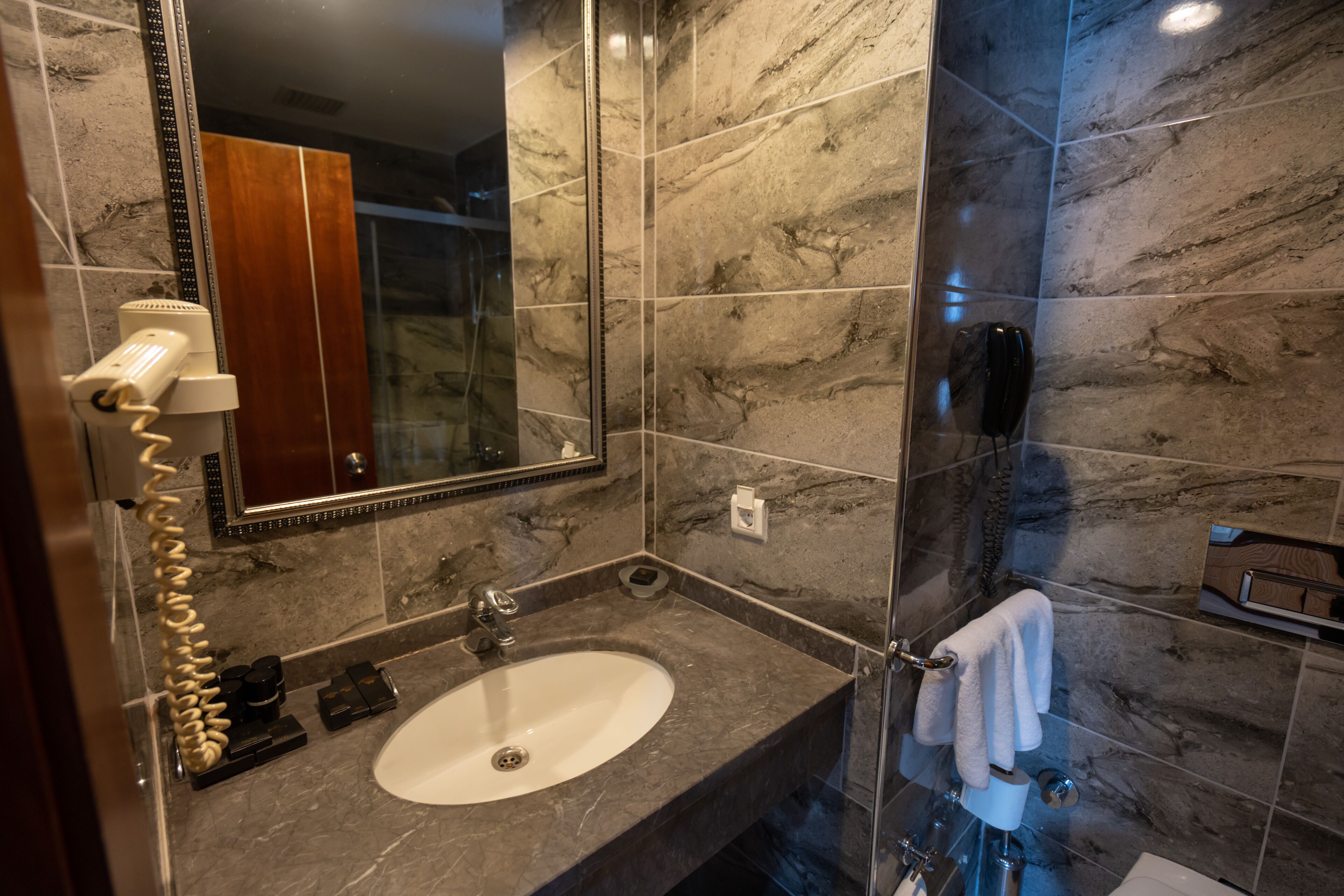 A bathroom with a marble sink, a mirror, a towel rack, and a shower area.