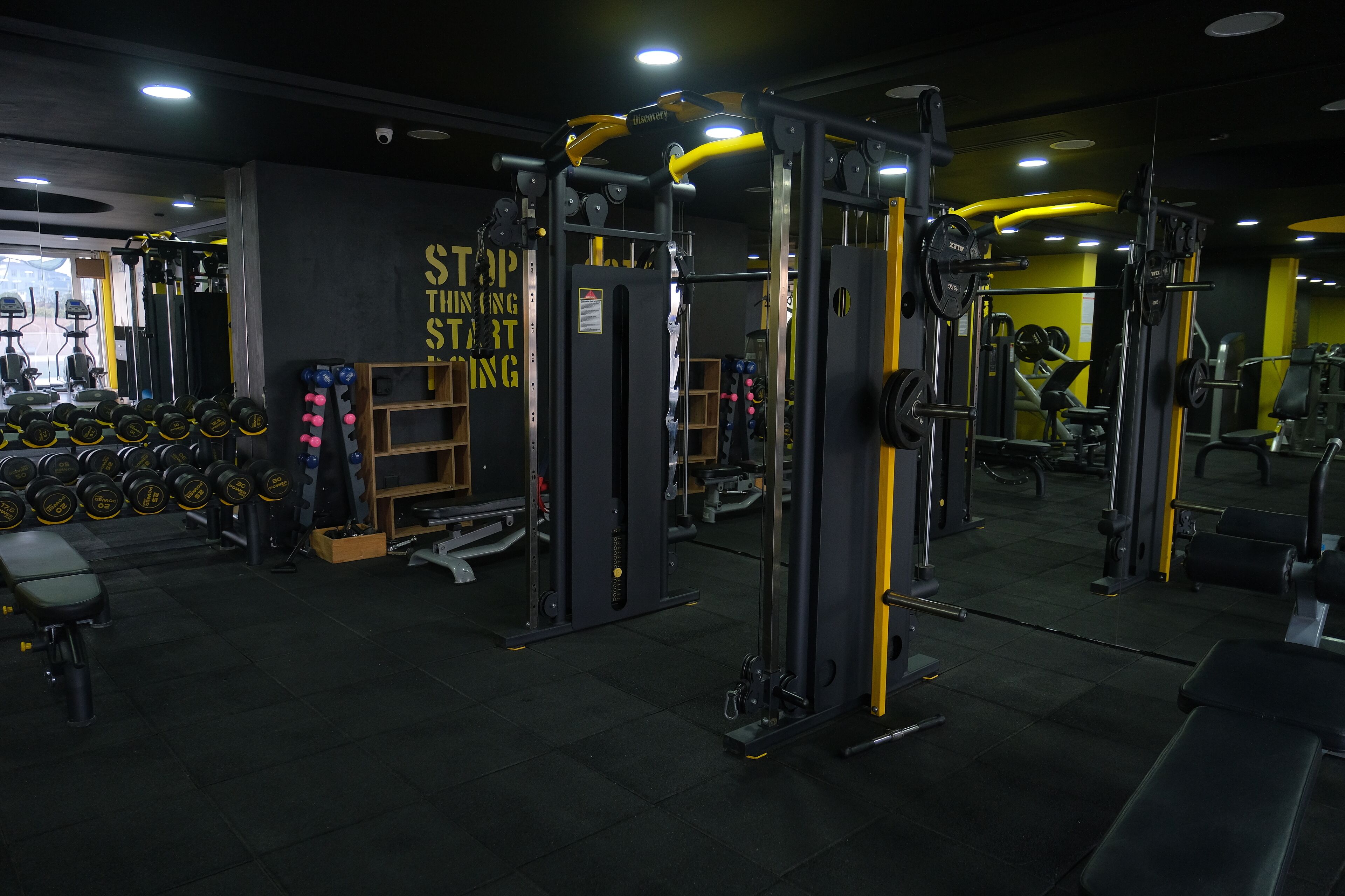 A gym with weightlifting equipment, dumbbells, and a motivational wall.