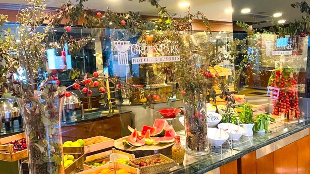 A buffet counter with various fruits and vegetables, glass containers, and decorative plants. - The Green Park Bostancı (Istanbul)