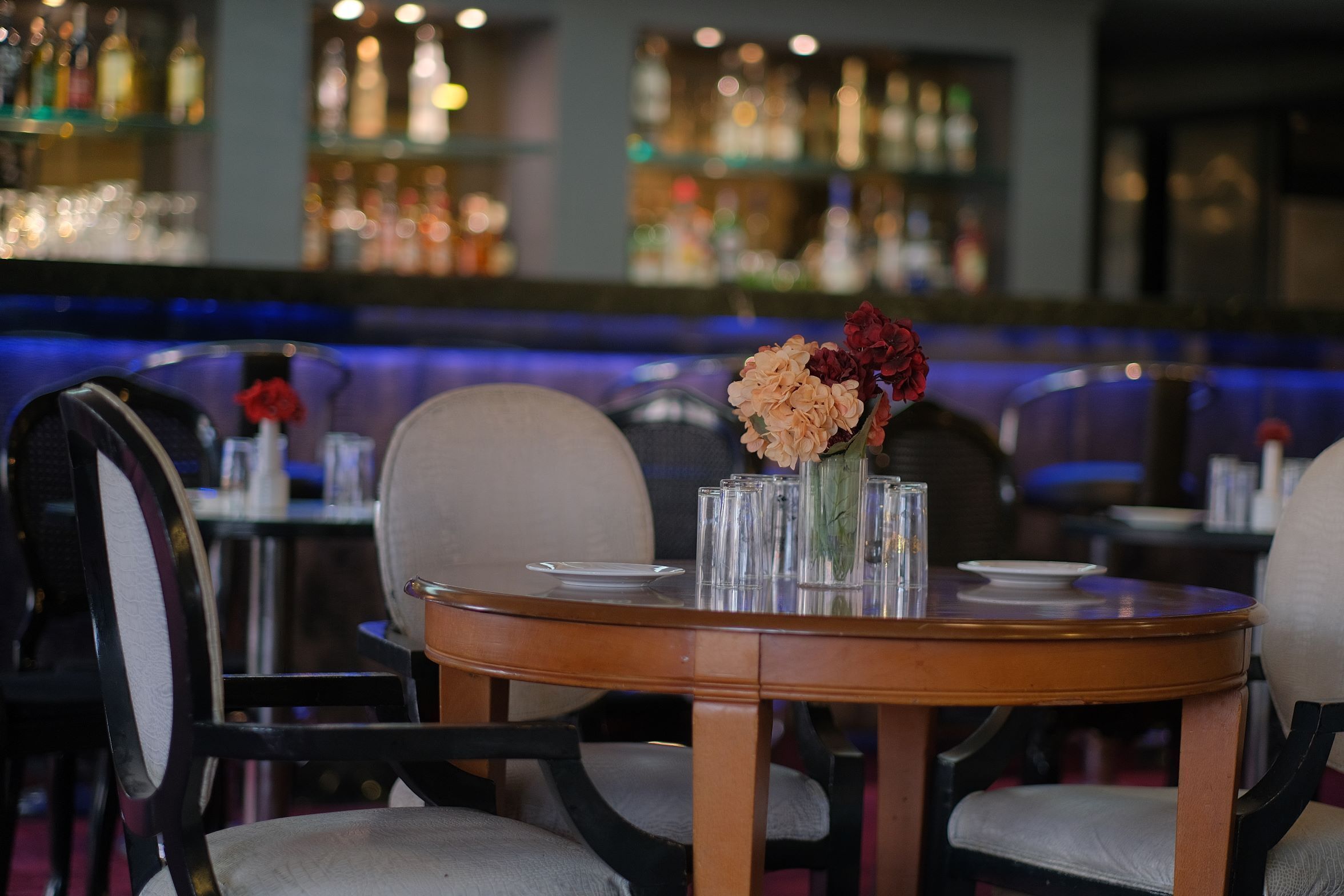 A round table with a vase of flowers, clear glasses, and a plate.