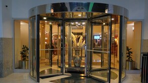 A revolving door entrance with a glass enclosure, a decorative vase, and potted plants. - The Green Park Bostancı (Istanbul)