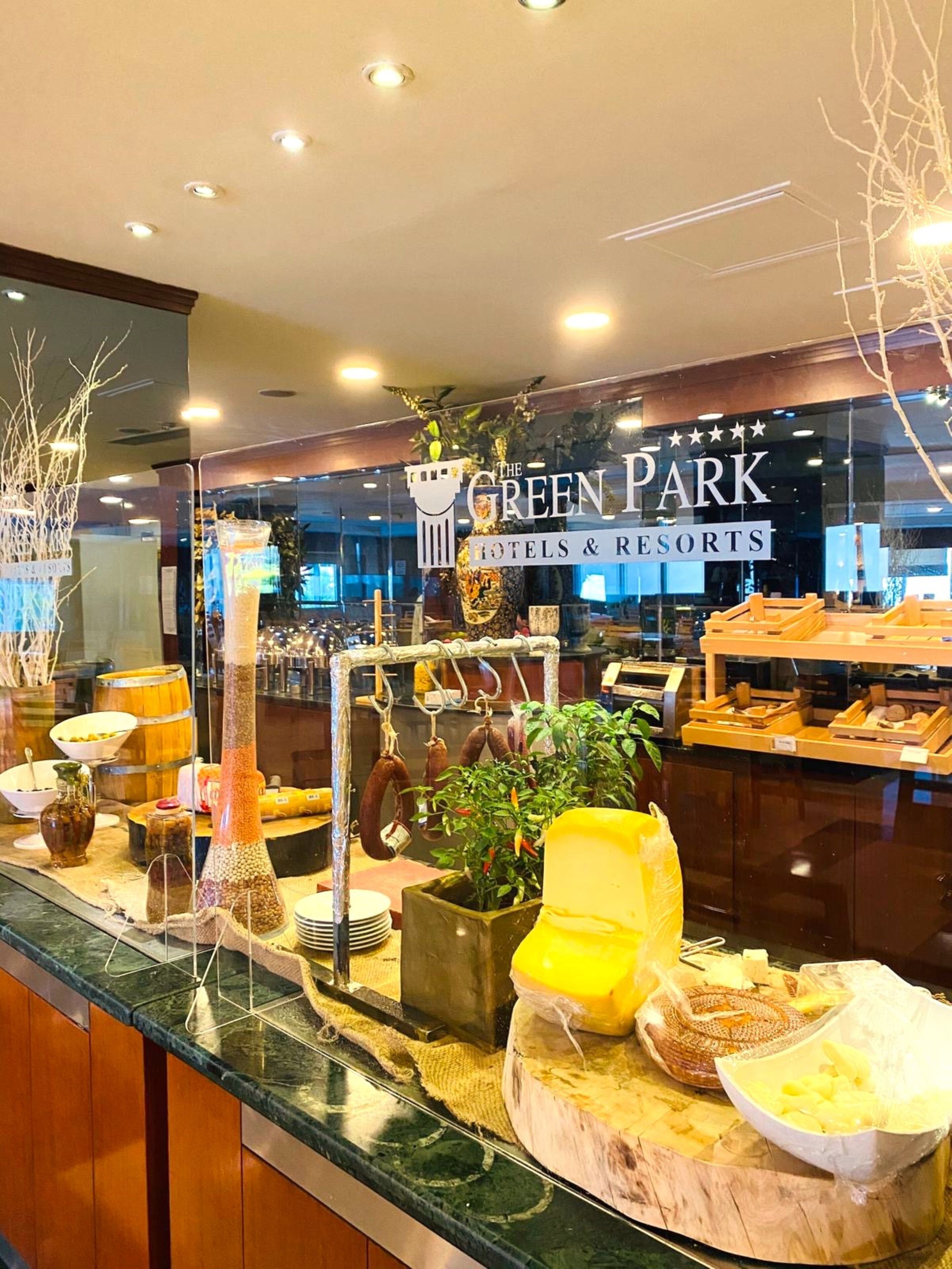 Buffetpöytä, jossa on tarjolla monenlaista ruokaa, sekä kyltti, jossa lukee Green Park Hotels & Resorts.