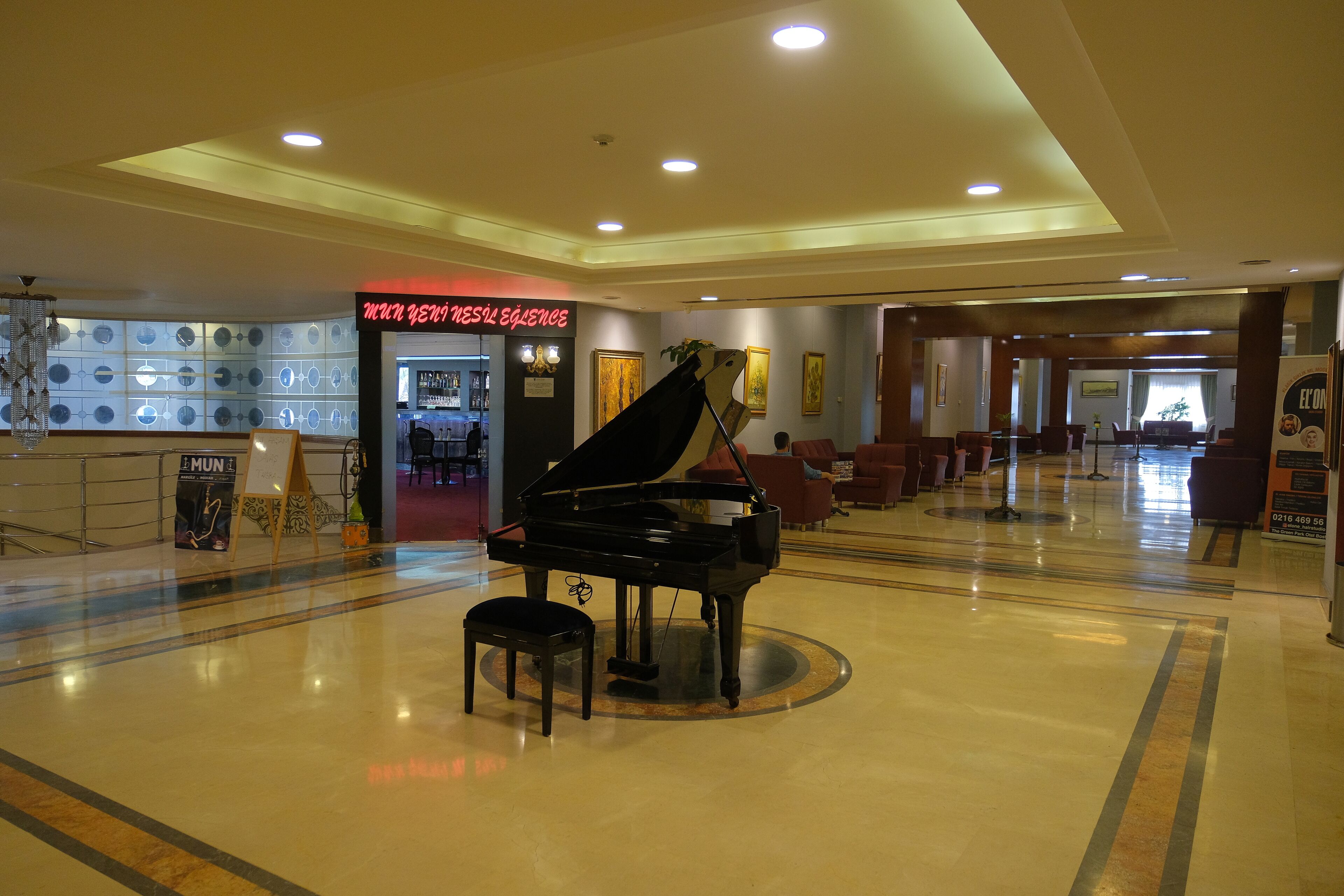 Un piano de cola imponente en un vestíbulo amplio con diseño moderno, una zona de bar y asientos cómodos.