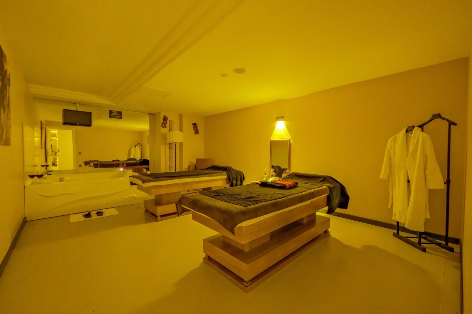 Une chambre d’hôtel dotée d’un grand lit, d’un coin salon séparé, d’une baignoire et d’un porte-peignoir.