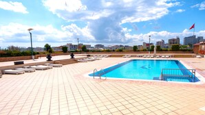 A swimming pool with lounge chairs and a cityscape in the background. - The Green Park Bostancı (Istanbul)