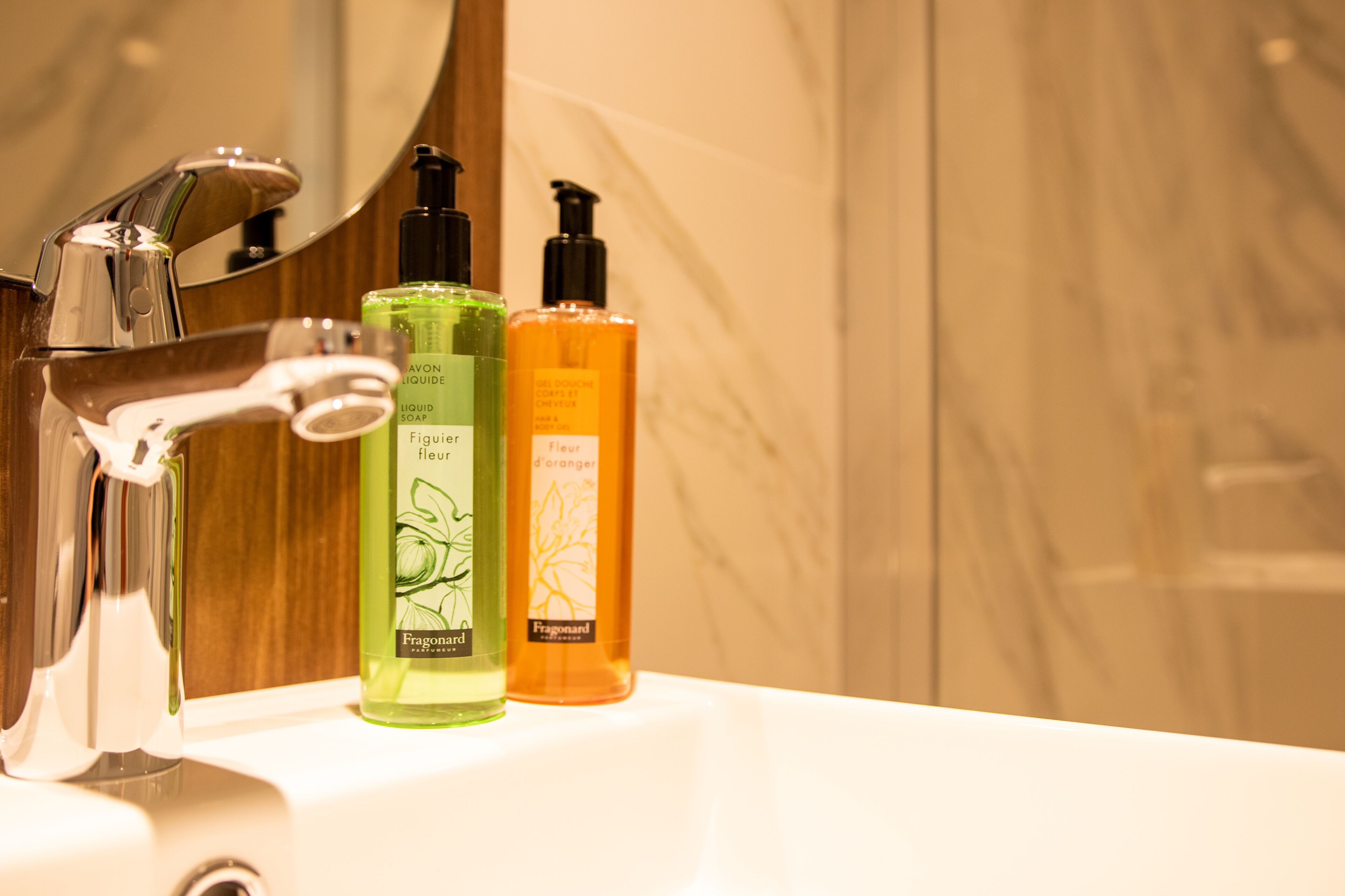 A bathroom sink with two bottles of Fragonard perfume and a chrome faucet.