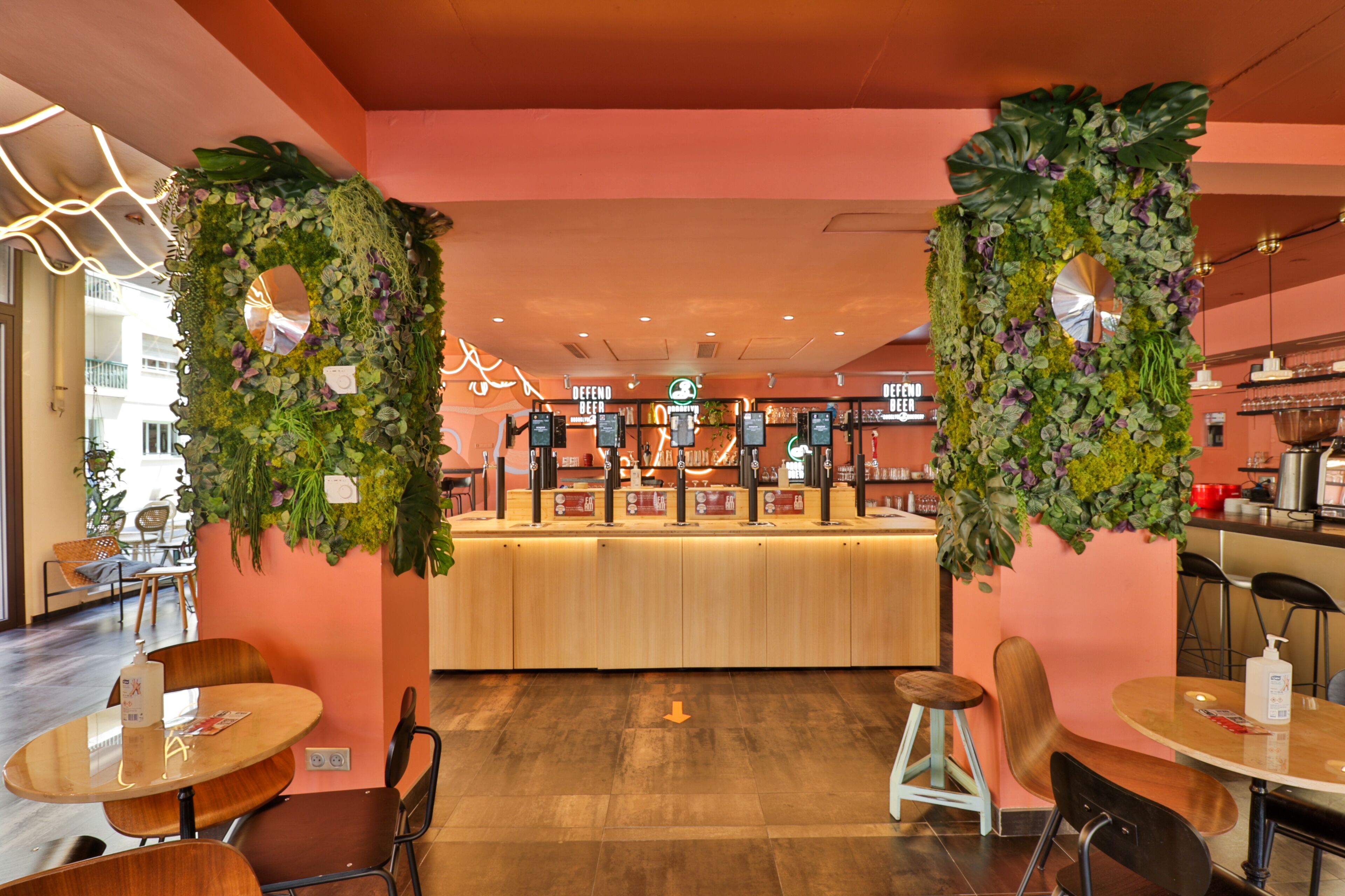 A restaurant interior with a central counter, seating area, and decorative plant walls.