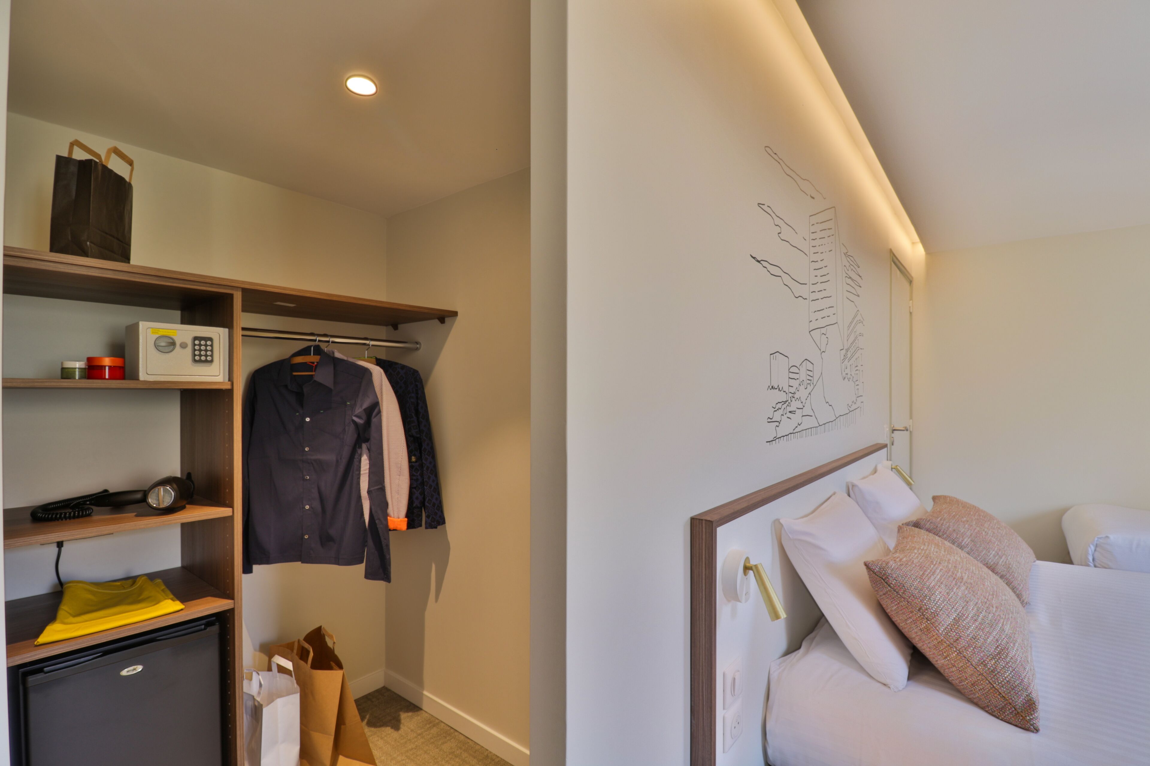 A hotel room with a bed, a desk, a wardrobe, and a small kitchenette.