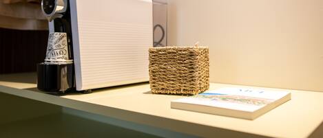 A coffee machine, a woven basket, and a book on a counter.