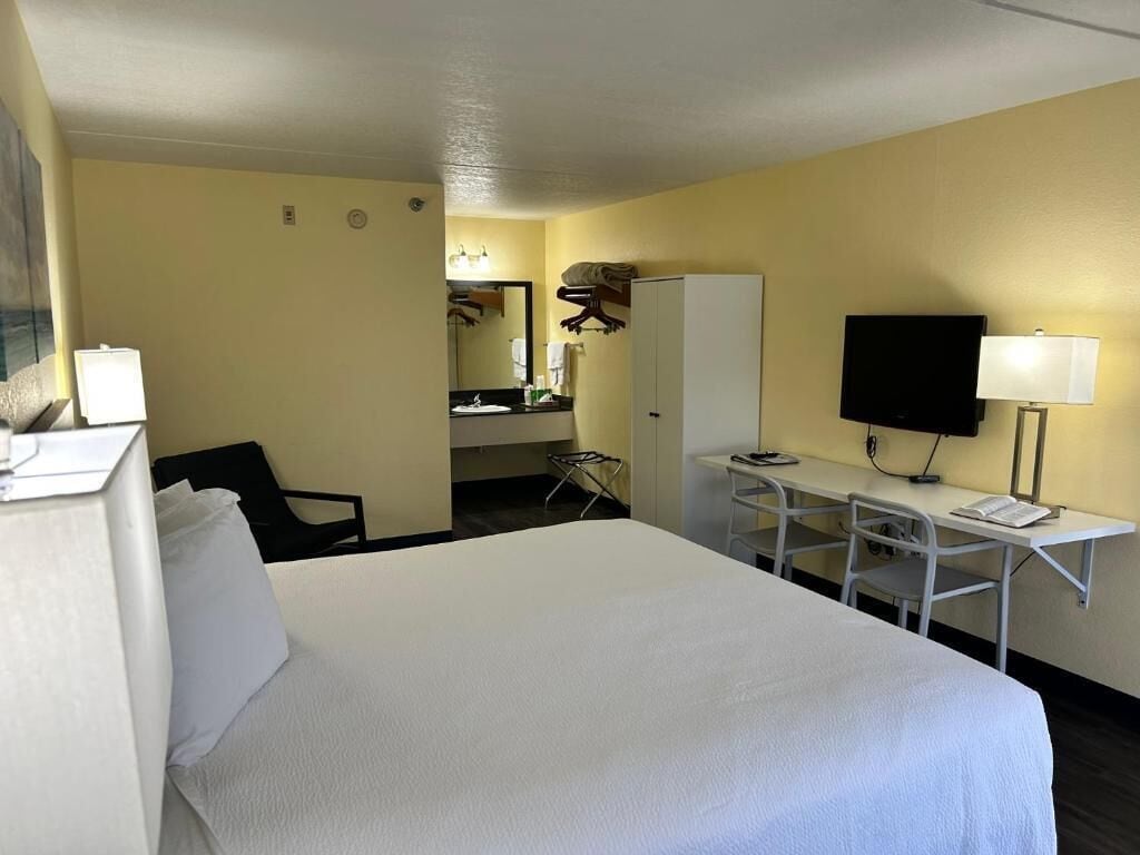 Una habitación de hotel con una cama, un escritorio, una silla, un televisor y un armario.