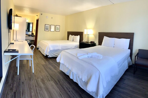 Une chambre d’hôtel avec deux lits, un bureau et une chaise.