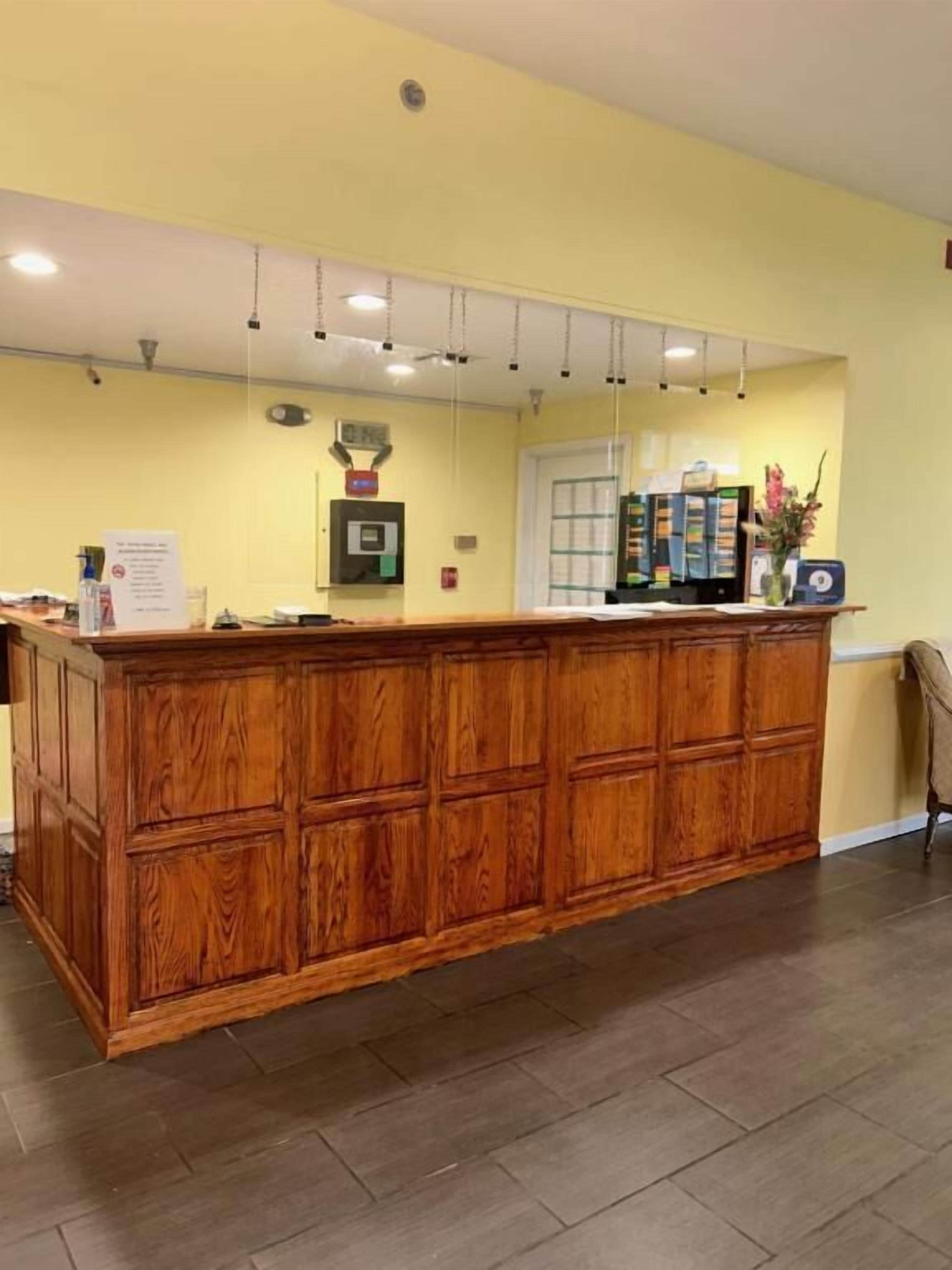 A reception area with a wooden counter, a door, and a wall-mounted information board.