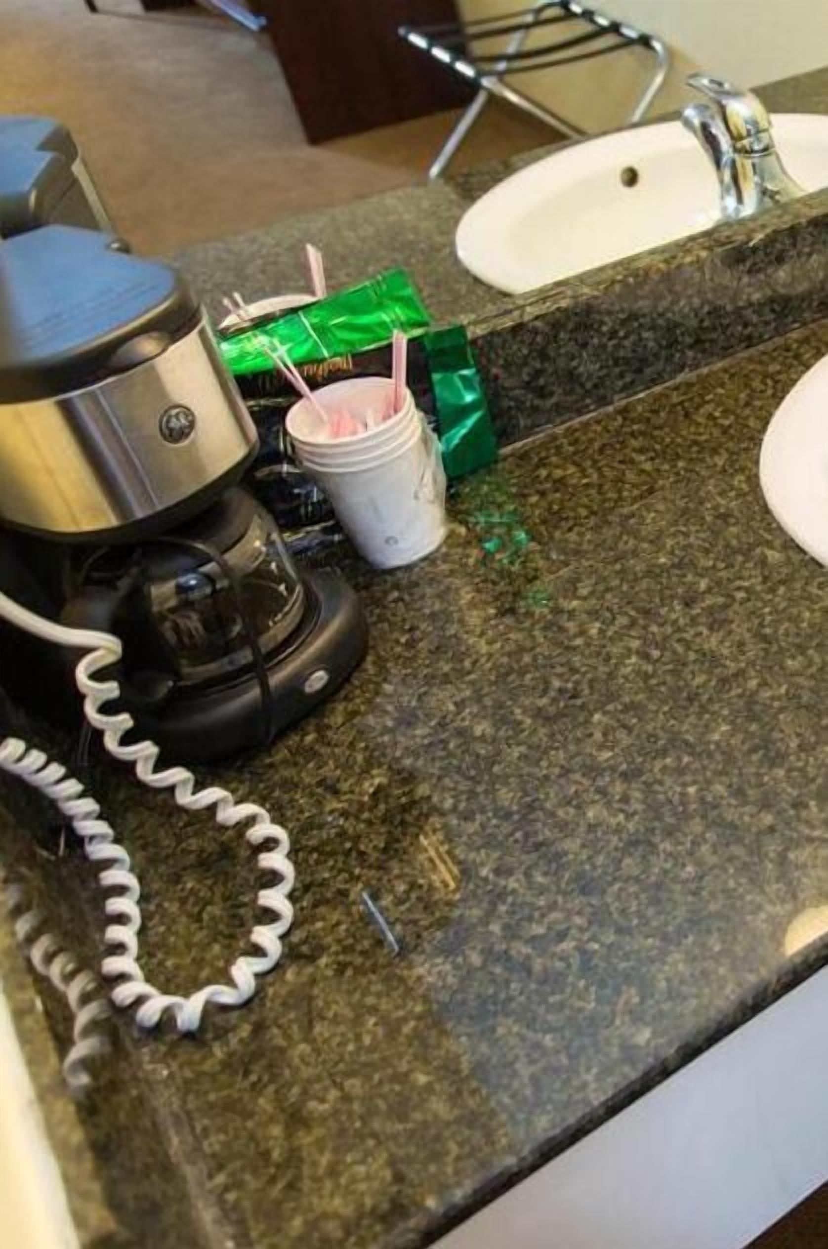 Un piano di lavoro in cucina con una macchina da caffè, una tazza di caffè e una scatola verde.