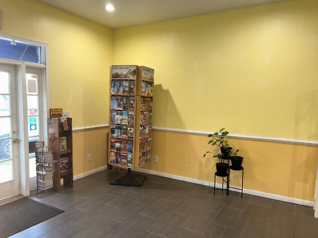 A hallway with a yellow wall, a bookshelf, and a door.