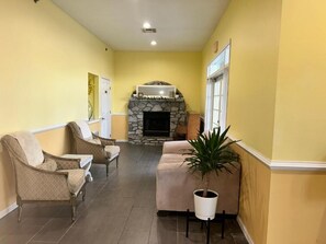 A hallway with a stone fireplace, two sofas, and a potted plant. - Seven Gables Inn (Branson)