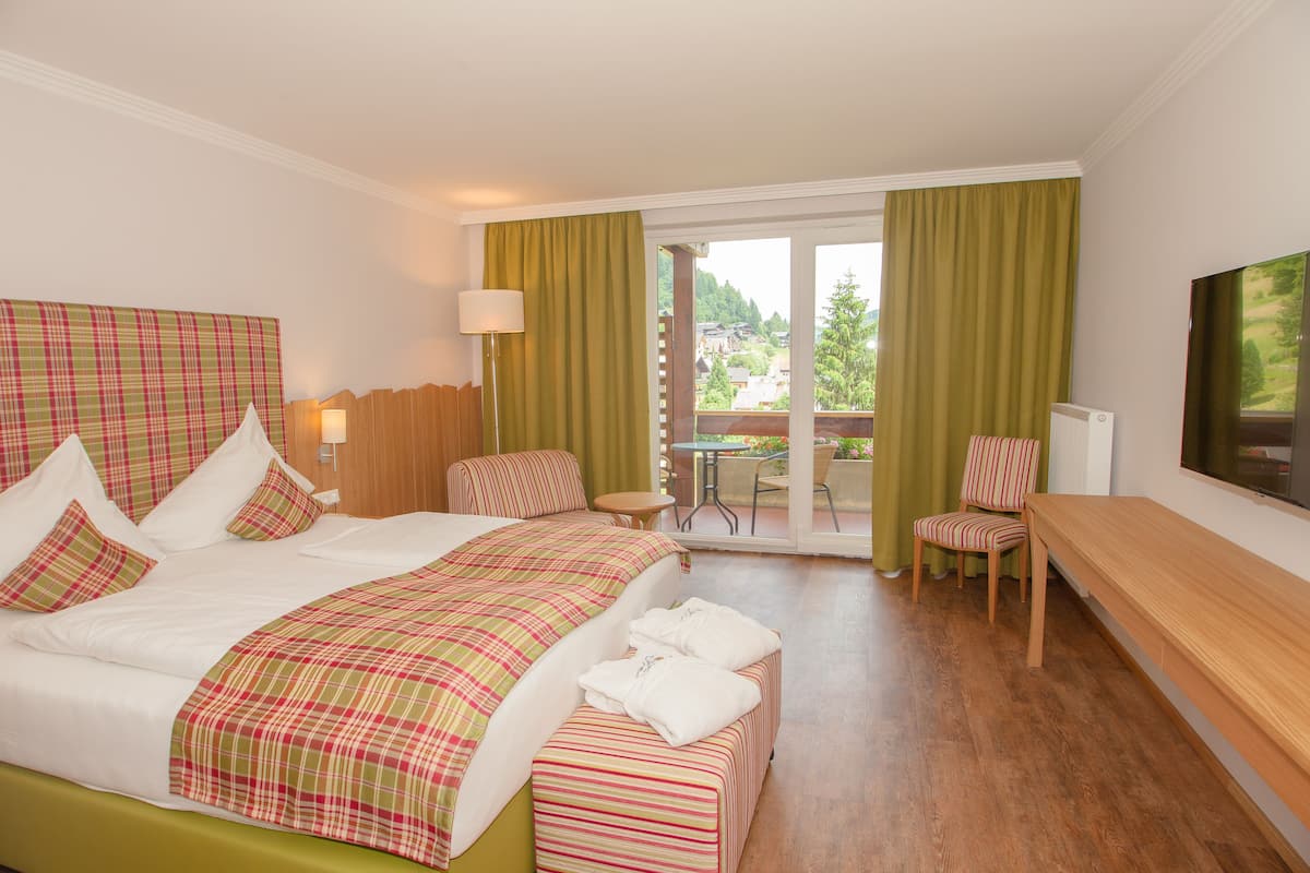 A hotel room with a large bed, a chair, a table, and a TV.