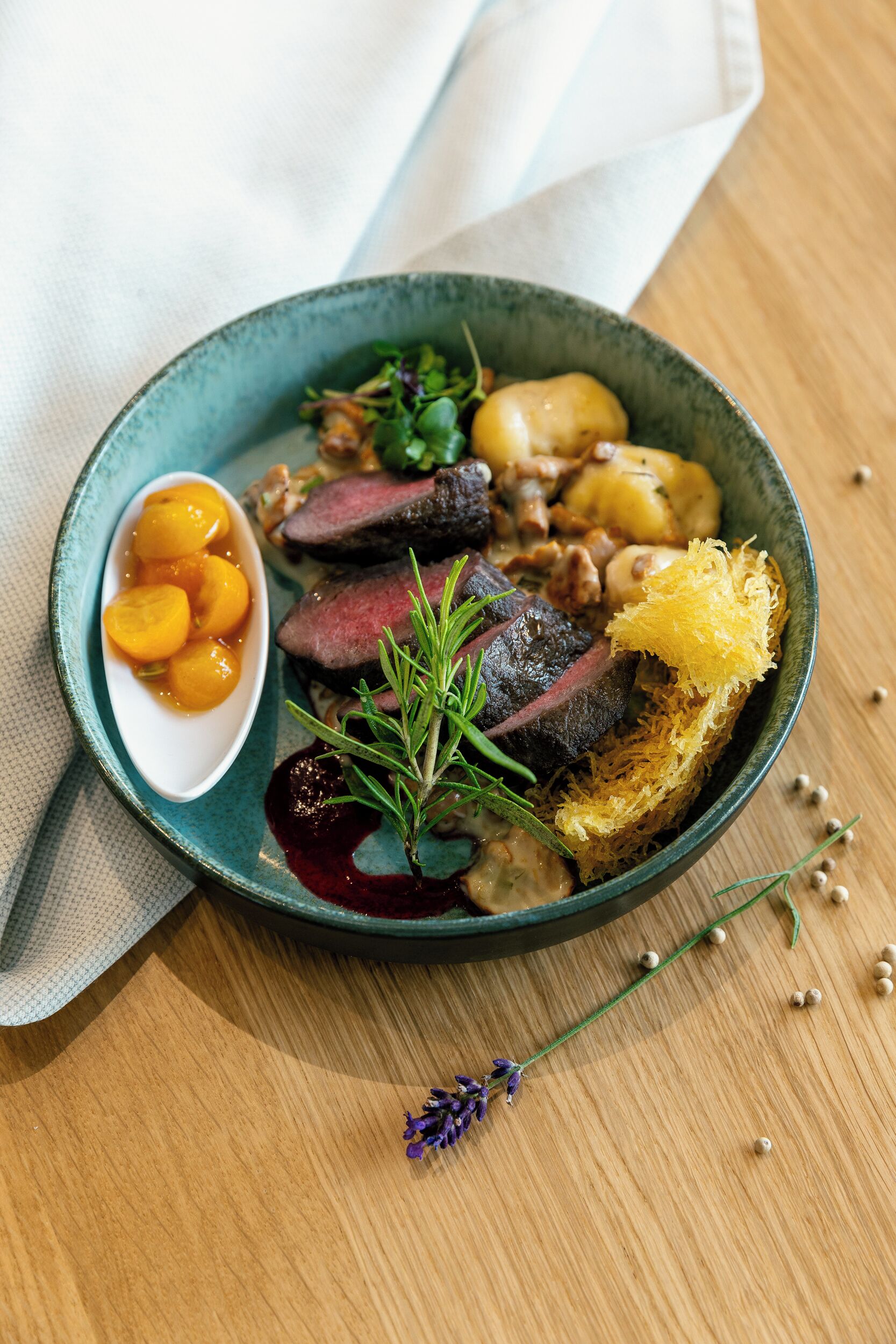 Un plato de comida con carne en rodajas, patatas y fruta como acompañamiento.