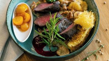 Un plato de comida con carne en rodajas, patatas y fruta como acompañamiento.
