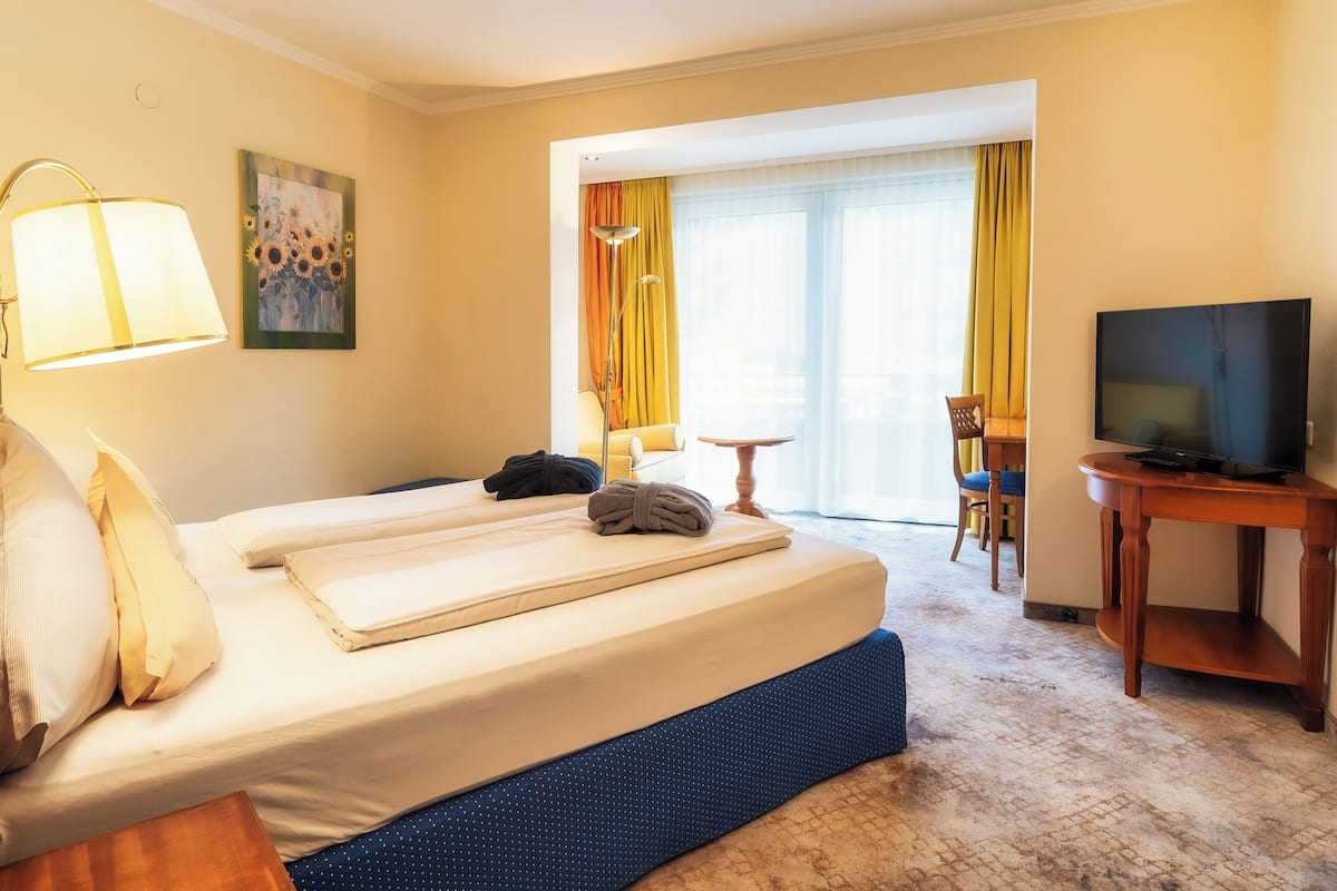 A hotel room with a bed, a television, a desk, and a window with curtains.