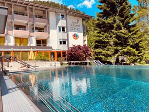 A hotel with a swimming pool, outdoor seating, and a sign indicating it is a 4-star establishment. - Evident Hotel Prägant (Bad Kleinkirchheim)