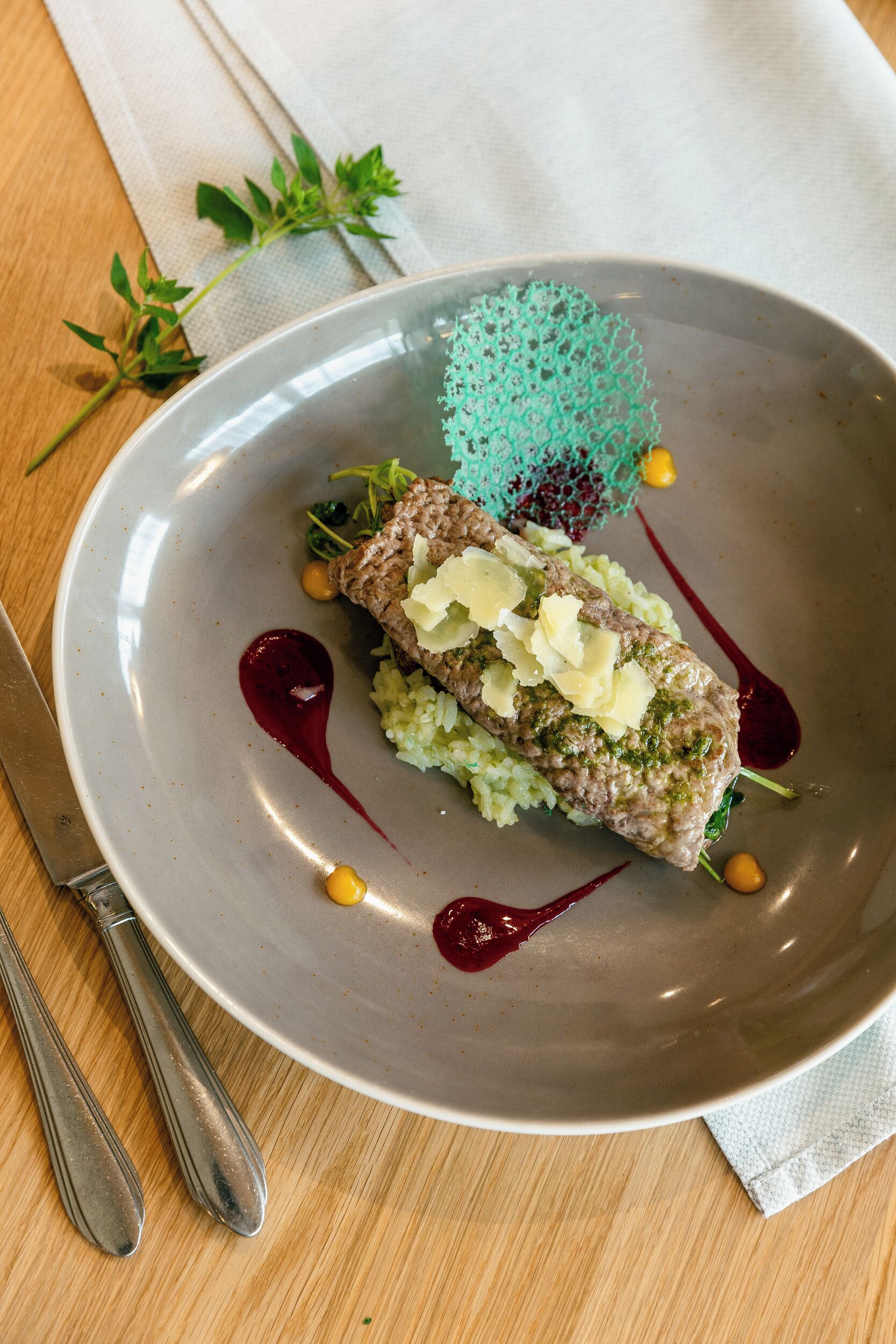 Un plato con un guiso de carne, vegetales verdes y salsa sobre una mesa.
